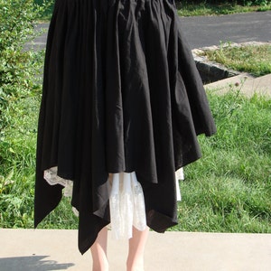 May include: A black asymmetrical skirt with a white lace trim. The skirt is gathered at the waist and falls to the ankles.