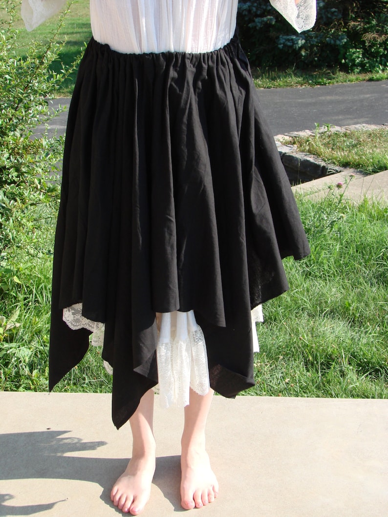 May include: A black asymmetrical skirt with a white lace trim. The skirt is gathered at the waist and falls to the ankles.