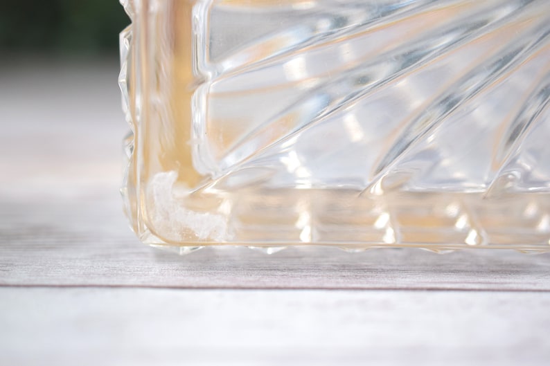 K&ouml;nnte beinhalten: Nahaufnahme eines transparenten Glasobjekts mit einem geometrischen, f&auml;cherartigen Muster. Das Objekt hat eine rechteckige Form mit einer strukturierten Oberfl&auml;che. Das Glas hat einen leichten Bernsteinton.