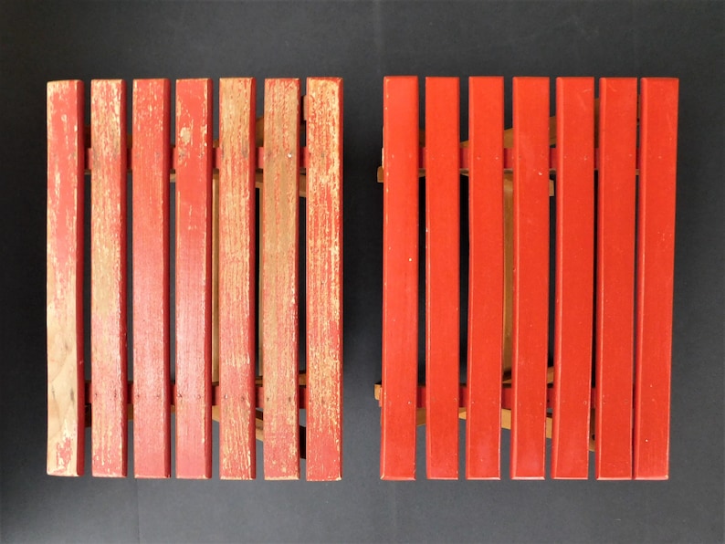 May include: Two red wooden folding chairs with a slatted design. The chairs are made of wood and have a red paint finish. The chairs are in good condition and have a vintage look.
