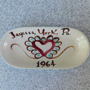 May include: White ceramic dish with a brown heart design and the text "Jaycees, York, Pa. 1964".