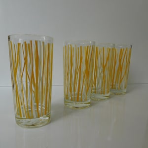 May include: Four clear glass drinking glasses with a yellow and white striped pattern.