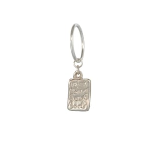 Op de afbeelding: Een zilveren oorring met een kleine, rechthoekige hanger met afgeronde hoeken. De hanger heeft een getextureerd, metalen oppervlak met de in reliëf aangebrachte woorden Love, Mind, Soul, Body in een handgeschreven, cursief lettertype.