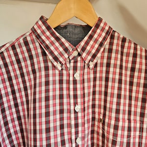 Puede incluir: Una camisa de manga larga a cuadros rojos y negros con un bolsillo en el pecho.