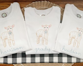 May include: Three white t-shirts with embroidered images of lambs. Each shirt has a different name embroidered below the lamb: Harrison, Grady, and Hudson.