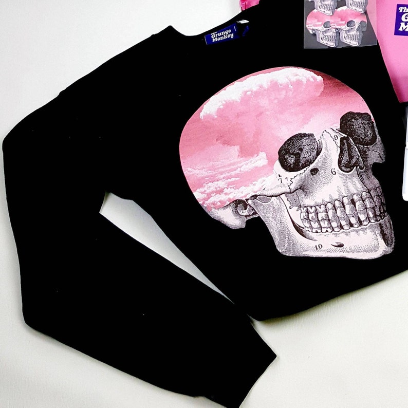 May include: Black sweatshirt featuring a graphic print of a skull with pink clouds inside. The label reads "Grunge Monkey".