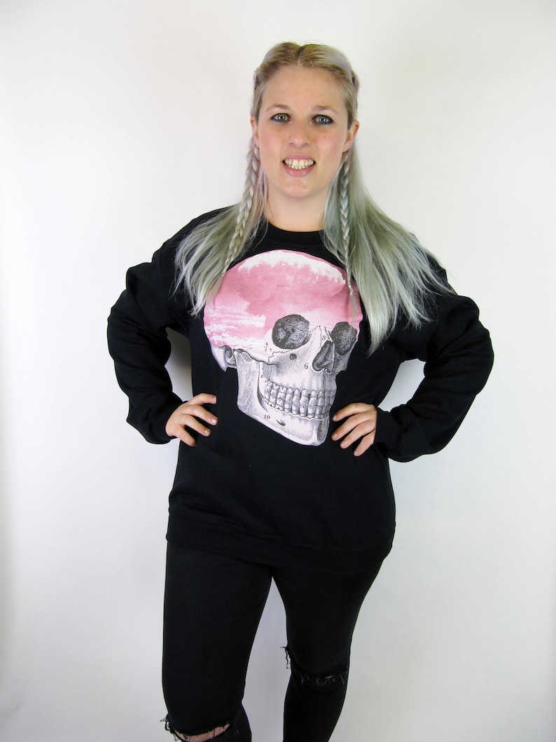 May include: Black sweatshirt with a large anatomical skull graphic printed on the front. The skull is pink and white.