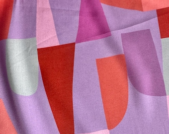May include: Close-up of a fabric with a geometric pattern. The design features shapes in shades of red, pink, purple, and gray. The fabric has a soft, slightly wrinkled texture, suggesting it may be a scarf or other textile.