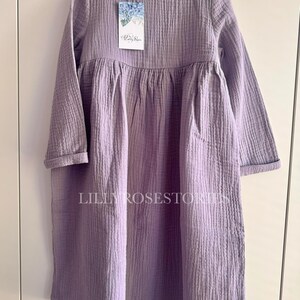K&ouml;nnte beinhalten: Ein lang&auml;rmeliges, lavendelfarbenes Kleid mit einem gerafften Rock und einem runden Ausschnitt. Das Kleid ist aus einem weichen, strukturierten Stoff gefertigt und hat eine lockere Passform.