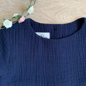 K&ouml;nnte beinhalten: Ein marineblaues Kleid mit einem R&uuml;schen-Saum und einem kleinen wei&szlig;en Etikett mit dem Wort "Rose" darauf.
