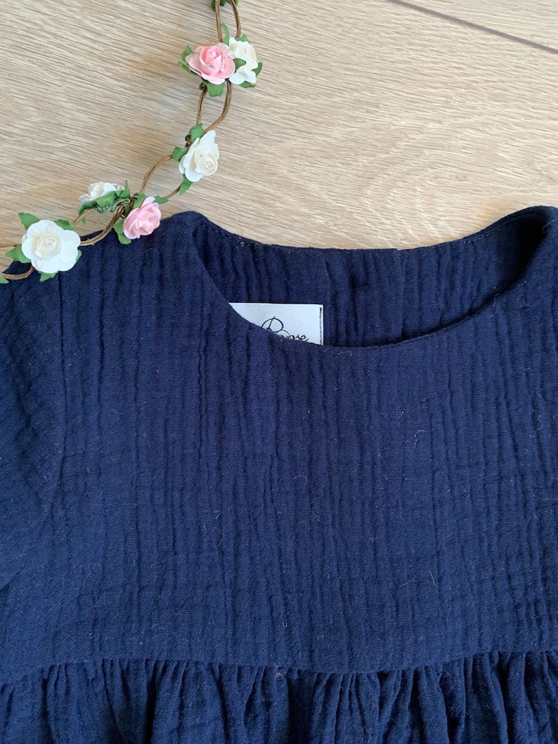 K&ouml;nnte beinhalten: Ein marineblaues Kleid mit einem R&uuml;schen-Saum und einem kleinen wei&szlig;en Etikett mit dem Wort "Rose" darauf.