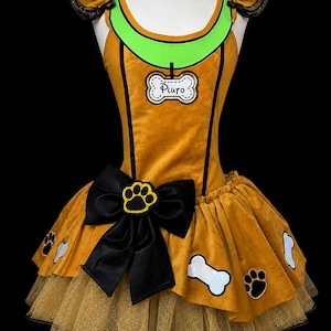 May include: A gold-colored dress featuring a bright green collar, a white bone-shaped tag with the name Pluto, and black ruffled sleeves. The skirt includes a large black bow with a yellow paw print, decorated with white bone and black paw appliques.