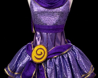Könnte beinhalten: Ein violettes Paillettenkleid mit drapiertem Oberteil, strukturiertem Taillenbereich und einem weiten Rock mit gerüschten Lagen. Das Kleidungsstück ist mit gold-braunen, spiralförmigen Kreismotiven an Schultern und Taille sowie Goldborten verziert.