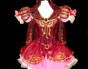 May include: A red and pink tulle tutu with gold embroidery and a red velvet bodice. The bodice has a red jewel in the center and a red bow at the waist. The tutu has a white lace trim and a red hood.