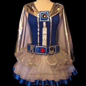 May include: A white tulle tutu with blue ribbon trim and silver glitter. A blue bodice with a silver cape and a silver and blue R2-D2 design is worn over the tutu.
