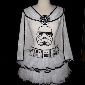 May include: White tutu with black trim and a white shirt featuring a black and white Stormtrooper graphic. The shirt has a black and silver Imperial symbol on the chest.