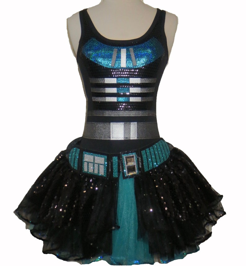 May include: A black and teal sequined dress with a black tulle skirt. The bodice features a silver and black striped design and a teal sequined panel. The skirt has a teal and black sequined belt with a silver buckle.