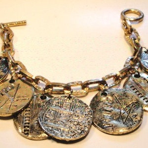 May include: A gold chain bracelet with multiple round charms, each featuring a different design. The charms are made of a combination of gold and silver metal and have intricate details.