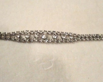 May include: A silver bracelet with a double row of clear rhinestones.