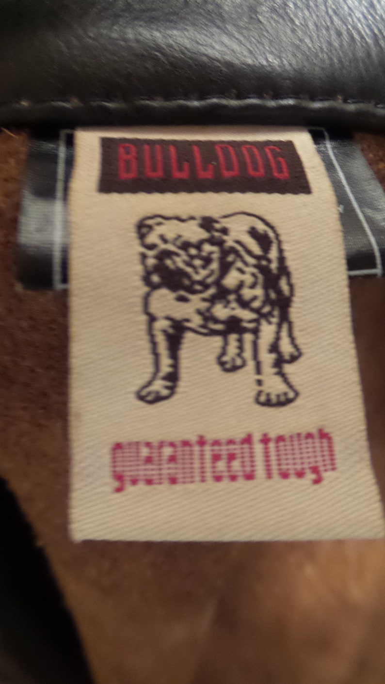 May include: Close-up of a tag with the word "BULLDOG" in red letters on a brown background. Below the word is an illustration of a bulldog. The words "guaranteed tough" are printed in pink.