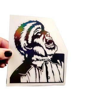 May include: A black and white sticker of a gorilla with its mouth open, roaring. The gorilla is wearing a collared shirt. The sticker has a holographic finish.