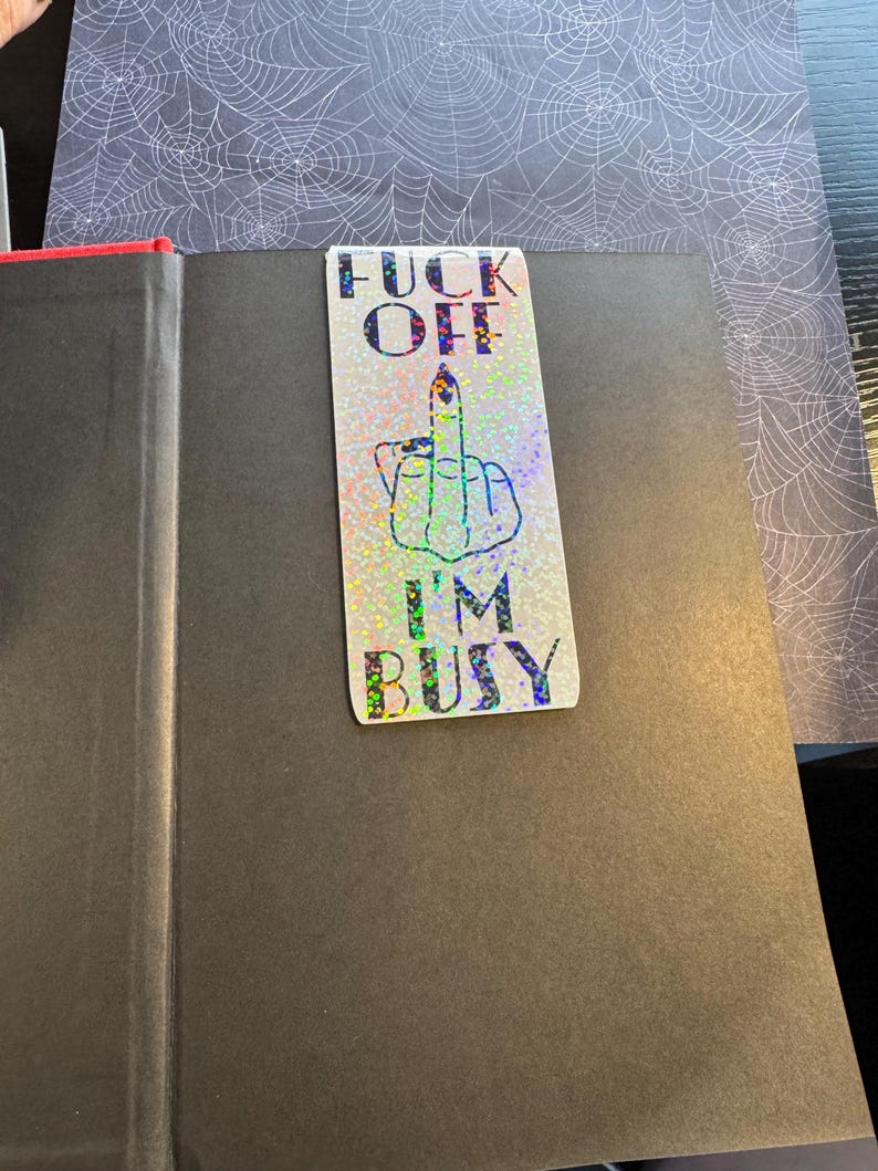 May include: A black and white sticker with a middle finger and the text "F**k Off I'm Busy" on a glittery background.