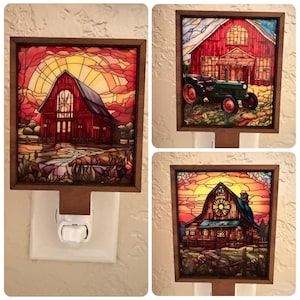 May include: Set of three decorative night lights featuring stained glass barn scenes. Each light has a wooden frame and a plug-in base. The artwork depicts barns with sunset backgrounds, and one includes a tractor.