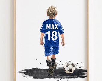 May include: A framed print featuring a young person in a blue soccer uniform with the name "MAX" and the number "18" on the back. A soccer ball rests near the person's feet, with a black and gray paint splash effect.