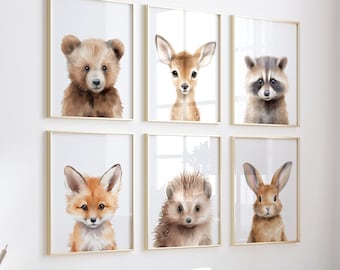 May include: Six framed watercolor prints of woodland animals: a bear, deer, raccoon, fox, hedgehog, and rabbit. Each animal is depicted with soft, natural colors and detailed fur. The frames are gold, and the prints are displayed on a white wall.
