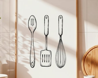May include: A framed print featuring line drawings of a slotted spoon, spatula, and whisk. The artwork is in black and white, with a light wood frame. The print is displayed on a wooden countertop with kitchen accessories.