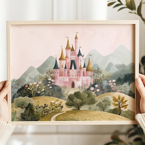 May include: A framed art print featuring a pink castle with gold-tipped towers, set amidst a lush landscape of green trees, flowers, and rolling hills. The background shows soft, muted mountains under a pale pink sky. The frame is made of light-colored wood.