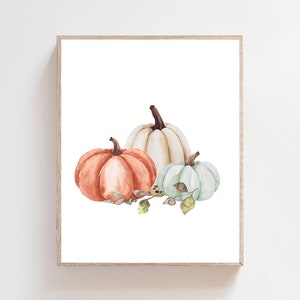 May include: A watercolor painting of three pumpkins. The pumpkins are orange, white, and light blue. The pumpkins are arranged in a cluster with green leaves and stems.