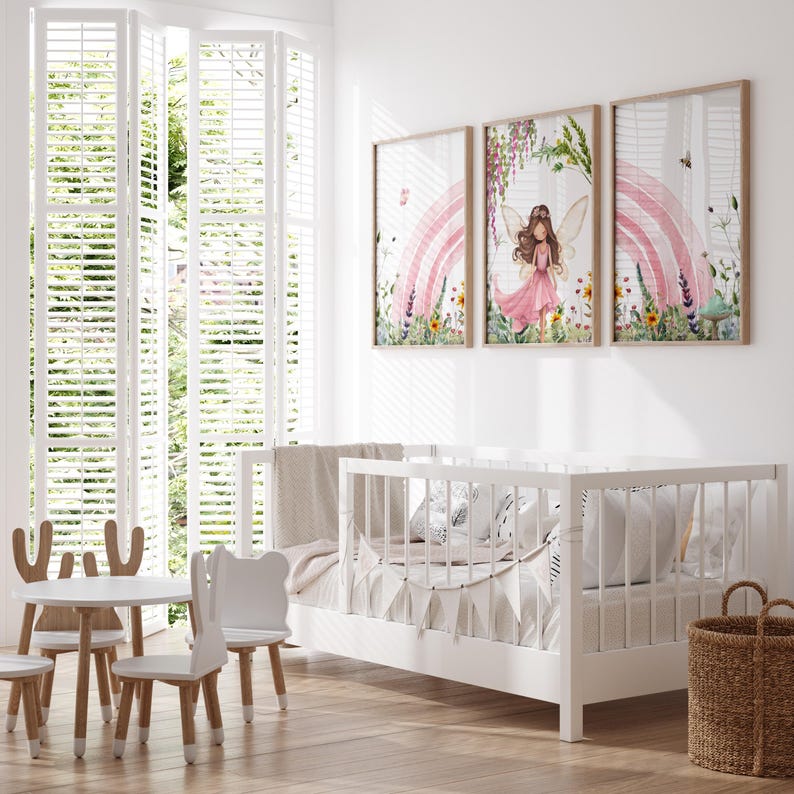 May include: Three watercolor prints featuring a fairy with wings and a pink dress standing in a field of flowers with a rainbow in the background. The prints are framed in a light wood frame.