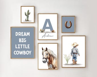 May include: A collection of framed art prints with a cowboy theme. The prints feature a cactus, a horseshoe, a horse, a child in cowboy attire, and the text "DREAM BIG LITTLE COWBOY". The prints are in gold frames.