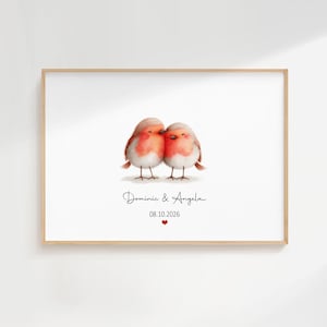 May include: A framed print showing two watercolour robins with red and white feathers, close together. The names "Dominic & Angela" are written below the birds, along with the date "08.10.2026" and a small red heart.