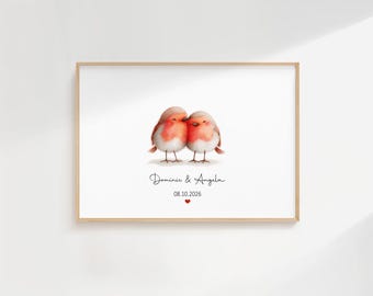 May include: A framed print featuring two watercolor robins, with red and white plumage, nestled together. Below the birds, the names "Dominic & Angela" are written, along with the date "08.10.2026" and a small red heart.