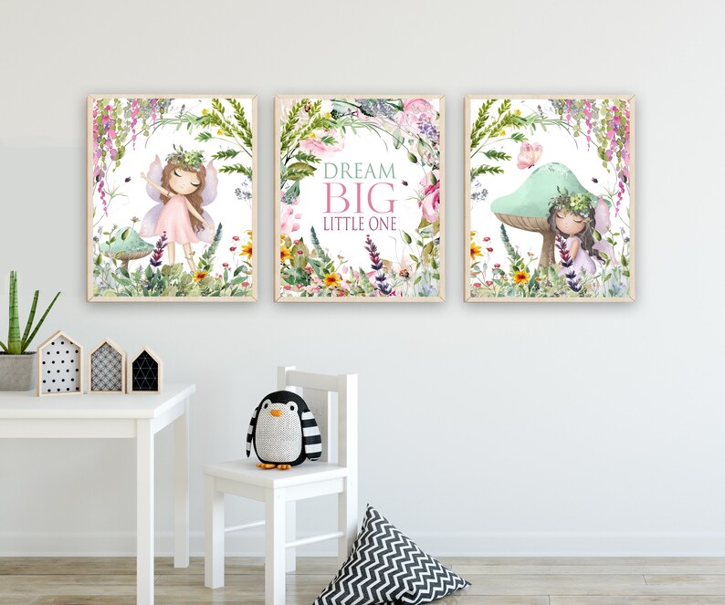 May include: Three framed prints with a whimsical fairy theme. Each print features a fairy with a pink dress and a floral crown, surrounded by flowers and greenery. The middle print has the text "Dream Big Little One".