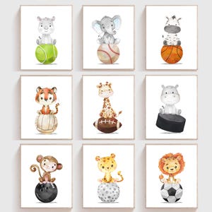 May include: Set of 8 printable nursery art prints featuring watercolor illustrations of animals balancing on sports equipment. The animals include a rhino, elephant, zebra, tiger, giraffe, hippopotamus, monkey, and lion. The sports equipment includes a tennis ball, baseball, basketball, football, hockey puck, and soccer ball.