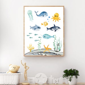 Peut inclure: Une illustration aquarelle d'une vari&eacute;t&eacute; de cr&eacute;atures marines, dont une baleine, une narval, une pieuvre, une m&eacute;duse et un poisson. L'illustration est sur un fond blanc avec une sc&egrave;ne oc&eacute;anique bleue et verte.