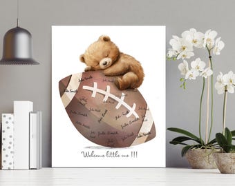 May include: A brown teddy bear is sleeping on a brown and white football. The football is covered in signatures. The text "Welcome little one!!!" is written below the football.