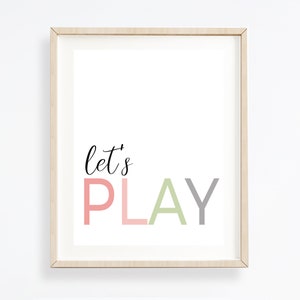 May include: A framed print with the text "let's PLAY" in pink, green, and gray lettering on a white background.