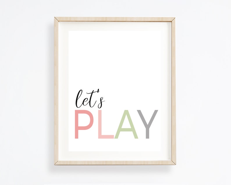 May include: A framed print with the text "let's PLAY" in pink, green, and gray lettering on a white background.
