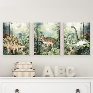 K&ouml;nnte beinhalten: Drei gerahmte Aquarellbilder von Dinosauriern in einer Dschungelkulisse. Die Bilder zeigen einen Stegosaurus, einen Tyrannosaurus Rex und einen Brachiosaurus.