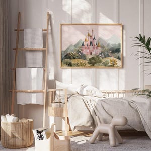 May include: A framed watercolor print of a pink castle with gold turrets, set against a backdrop of green mountains and a soft pink sky. The artwork is displayed in a light wood frame, adding a touch of elegance to the children's room decor.