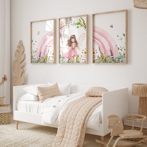 May include: Three framed prints with a watercolor style design. The center print features a fairy with pink wings and a pink dress standing in a field of flowers. The left and right prints feature a rainbow and flowers.