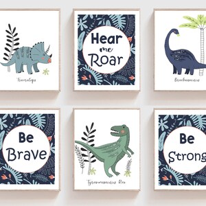 May include: Set of six blue and green dinosaur themed nursery prints with motivational phrases. The prints feature illustrations of dinosaurs, including a Triceratops, Brachiosaurus, and Tyrannosaurus Rex. The phrases on the prints include "Hear me Roar", "Be Brave", and "Be Strong".