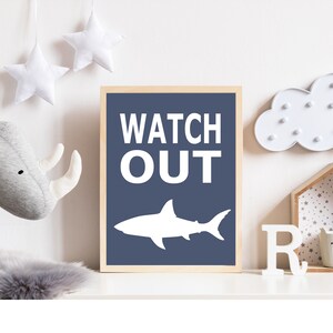 Op de afbeelding: Een blauwe en witte kinderkamerprint met een haaien silhouet en de tekst "WATCH OUT".