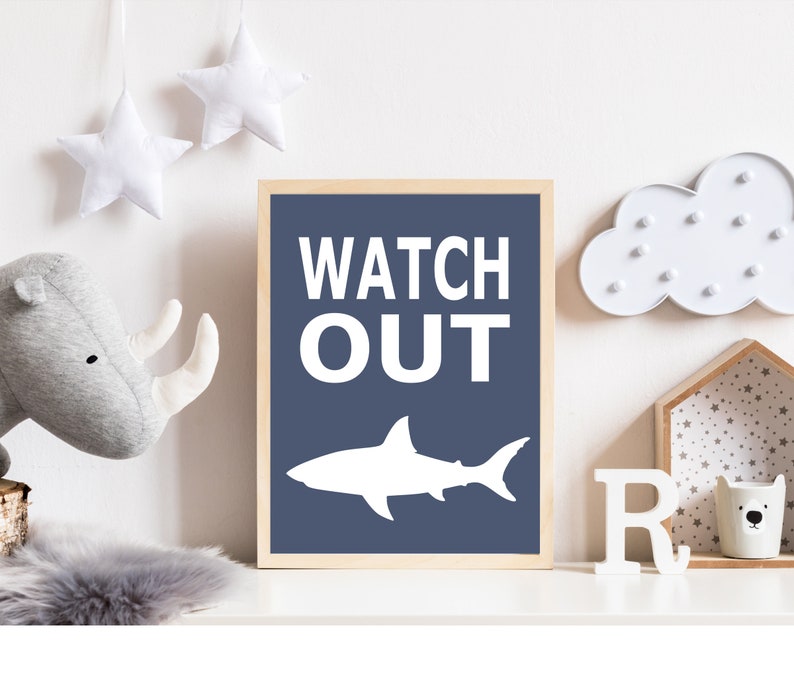 Op de afbeelding: Een blauwe en witte kinderkamerprint met een haaien silhouet en de tekst "WATCH OUT".