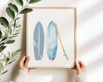 Puede incluir: Una impresión enmarcada de acuarela de tres tablas de surf azules y blancas, dos de pie y una acostada horizontalmente, sobre un fondo blanco.