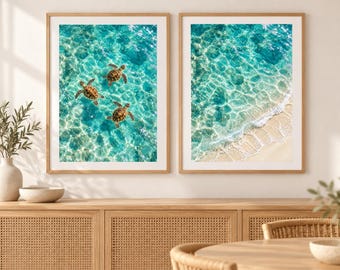 May include: Two framed wall art prints featuring aerial views of the ocean. The left print shows three sea turtles swimming in clear turquoise water. The right print displays a sandy shoreline with gentle white waves meeting the blue sea.